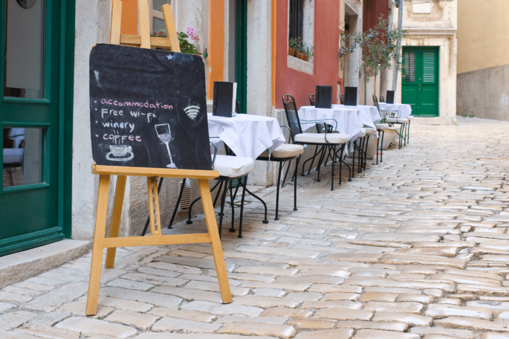 Leben in Kroatien 2025/26 – gemütliches Straßencafé in einer Altstadtgasse mit Kopfsteinpflaster, mediterranem Flair und typischer kroatischer Atmosphäre.