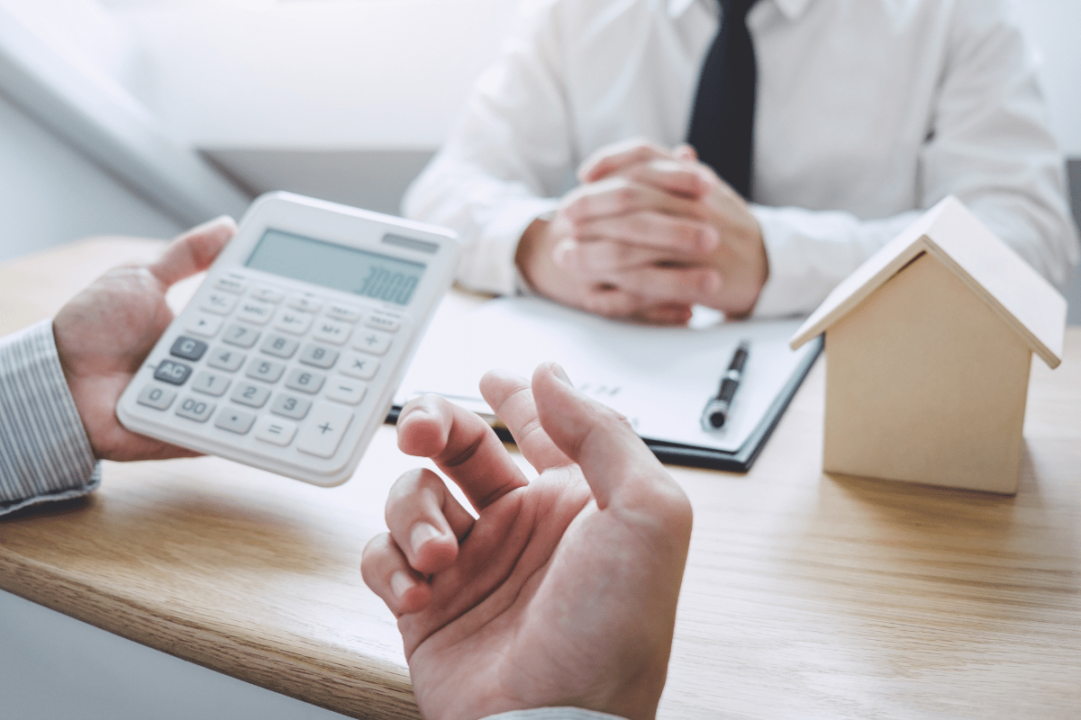 Immobilienkauf Kroatien – Käufer und Berater besprechen Steuern und Kaufnebenkosten mit Taschenrechner und Hausmodell